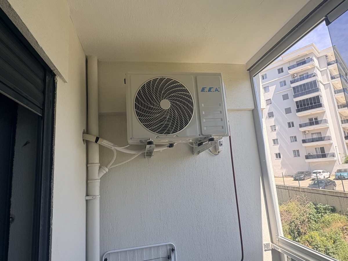Balkon köşesinde tamamlanmış dış ünite montajı; konsol, izoleli boru ve drenaj hattı düzenli