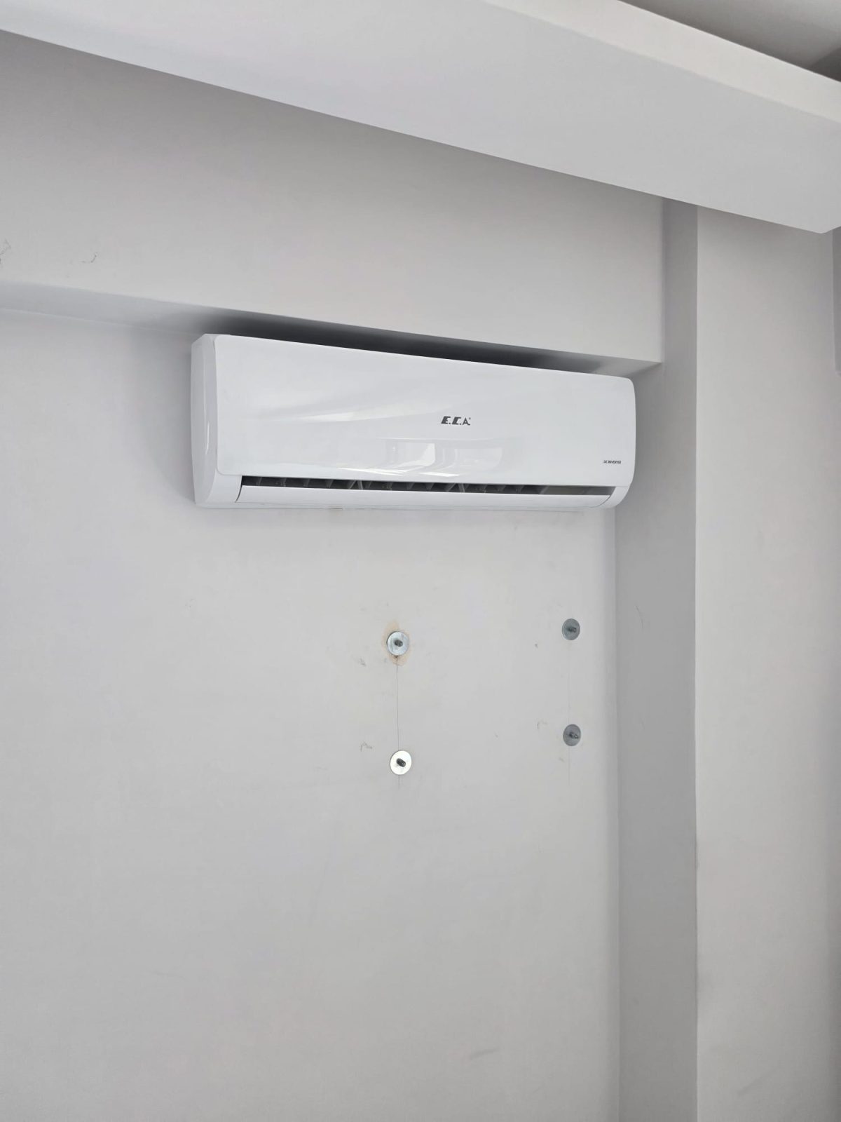 Boş bir odada duvara asılı iç ünite; panel kapalı ve gövde temiz
