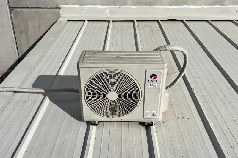Metal çatı kaplaması üzerine yerleştirilmiş dış ünite ve drenaj hattı