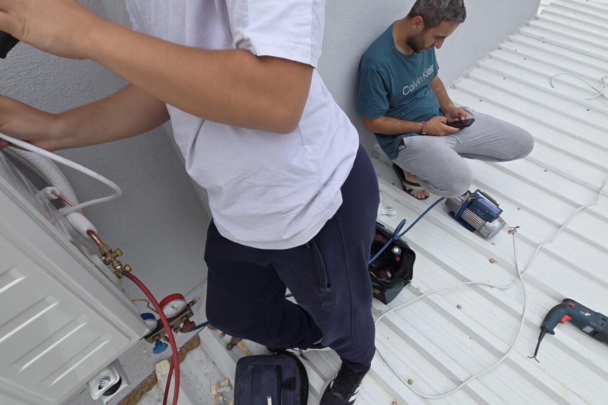Metal çatıda ekip çalışması; alet çantası ve hatlar hazır