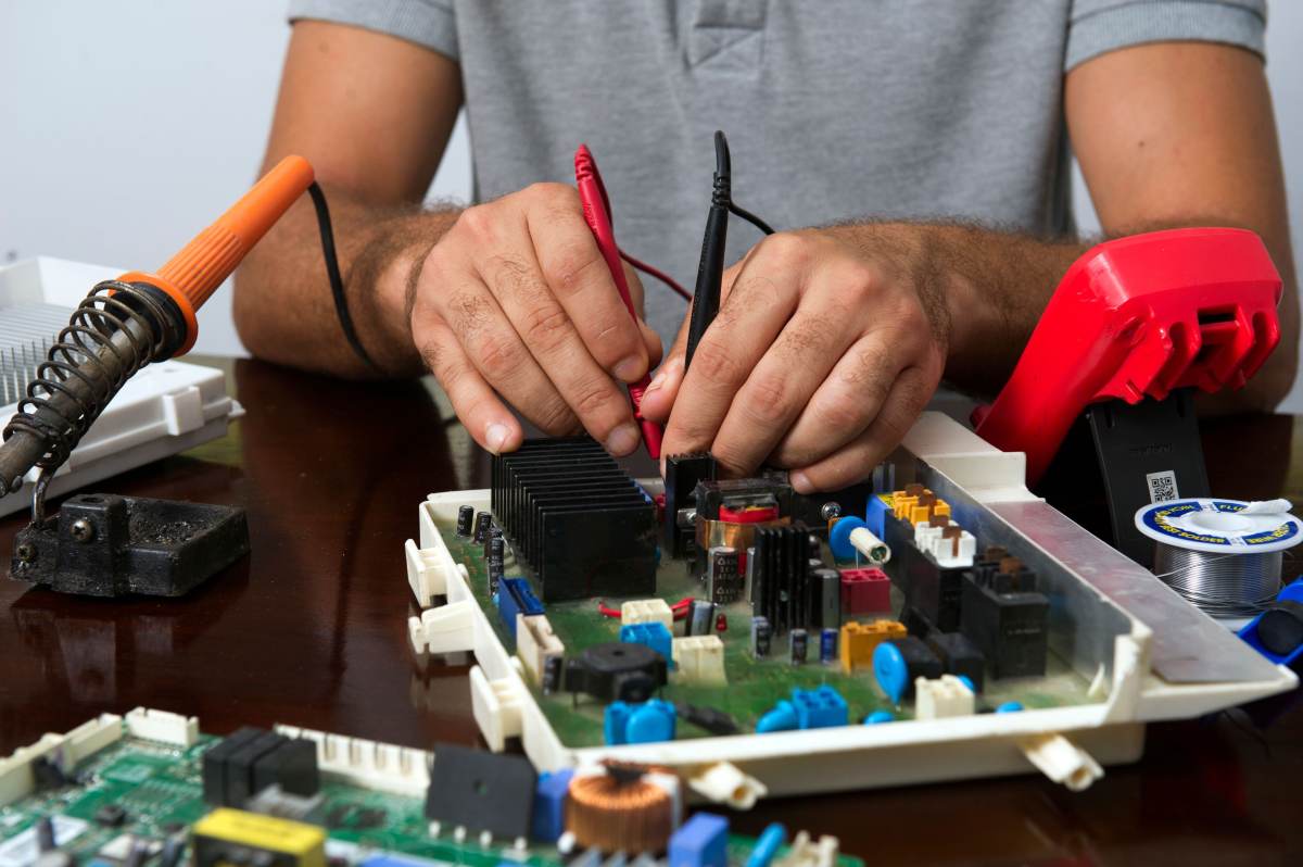 Teknisyen klima kontrol kartı üzerinde multimetre problarıyla ölçüm yapıyor